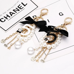 Elegant pearl keychain with black bow, gold number 5, and Eiffel Tower charm for handbags