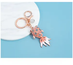 Detail of rose gold goldfish keychain with cat-eye stone scales and enamel tail