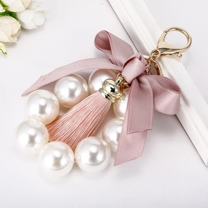 Porte-clés élégant en perles avec nœud en soie rose et pompon pour décor de sac