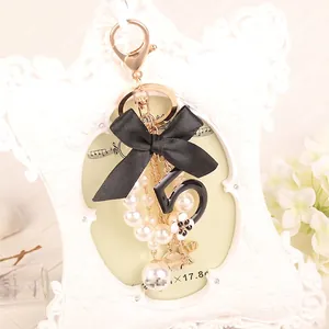 Fashionable keychain with black silk bow, white pearl string and black number 5 charm
