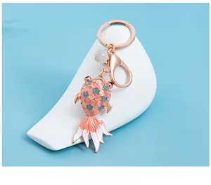 Detailed macro of rose gold goldfish keychain with cat eye stones and pink enamel tail