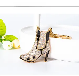 Detail view of gold high heel boot keychain with white rhinestones and black enamel accents