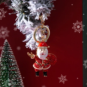 Christmas Santa Claus keychain with red rhinestones on snow-covered pine branch