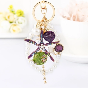Detail of starfish and shell keychain with purple rhinestones, pearls and golden chain