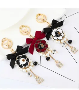 Detail of camellia bag charm with silk bow, faux pearls and perfume bottle pendant