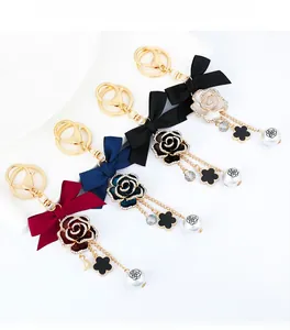 Detail view of floral charms with ribbon bow and pearl on golden metal keychain hook