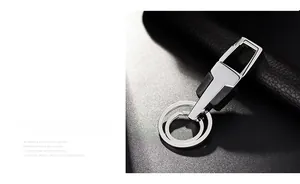 Detail of silver metal car keychain with dual rings and leather texture contrast