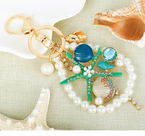 Detail of starfish keychain with rhinestones, sea shells, and pearls on metal clasp