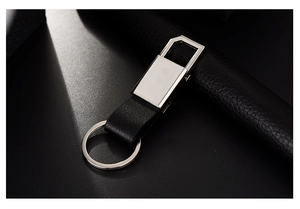 Close-up of polished silver metal car keychain with black leather on dark texture