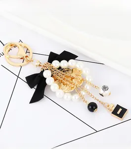 Detail of elegant black ribbon bow keychain with pearls and perfume bottle pendant