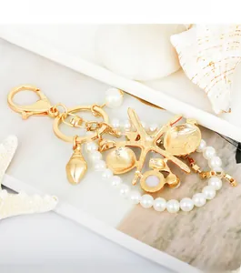 Detailed view of gold starfish and seashell keychain with elegant white pearls