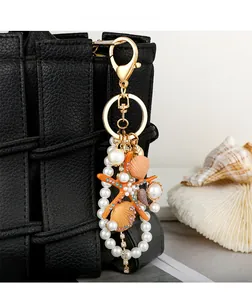 Detailed view of rhinestone starfish and pearl charm hanging on a luxury black leather bag