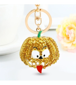 Macro shot of gold-plated pumpkin keychain with yellow crystals and funny face design
