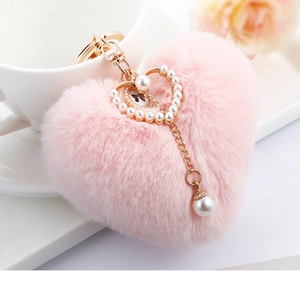 Detailed view of pink faux fur heart keychain with gold ring and elegant pearl charms