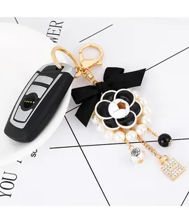 Detail of camellia pearl keychain with black bow and perfume bottle charm for car keys