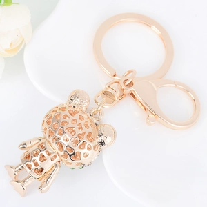 Rose gold metal bear keychain featuring hollow heart patterns and green crystal eyes