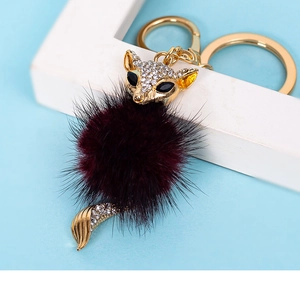 Detailed view of fox keychain with purple mink fur pompom and golden rhinestones