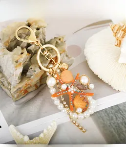 Detail of starfish and shell keychain with pearls and rhinestones on a marine background