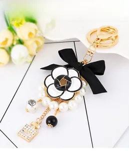 Detail of camellia floral charm with bow and pearl keychain on ceramic tray