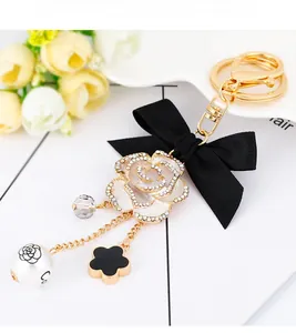Detail of camellia keychain with black bow, crystal bead and pearl on gold ring