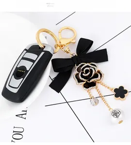 Detailed shot of camellia keychain with black bow and clover pendant on car key