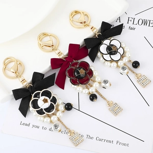 Elegant camellia bow pearl keychains in black, burgundy, and white silk with gold charms