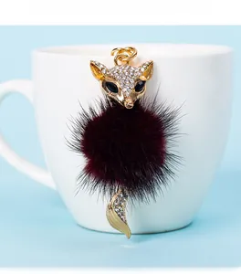 Detail of fox head key ring with sparkling rhinestones and burgundy fur pompom