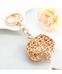 Detail of apple-shaped gold keychain with hollow heart patterns and lobster clasp