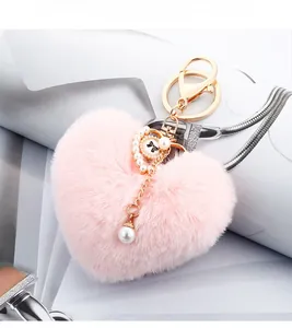 Close-up of pink heart-shaped plush keychain with pearl charms and gold metal hardware
