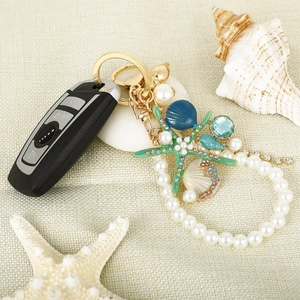 Starfish and seashell keychain with pearls and rhinestones on a black car key