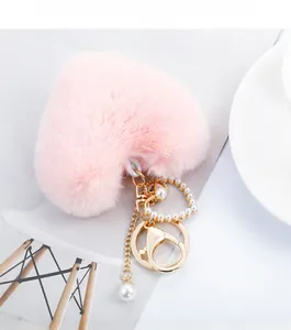 Detail of pink heart plush keychain with golden chain, lobster clasp and white pearl