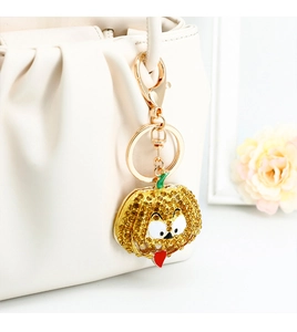 Detailed view of pumpkin keychain with yellow rhinestones on cream leather handbag