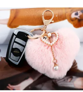 Close-up of pink heart faux fur keychain with pearl tassel and golden metal hardware