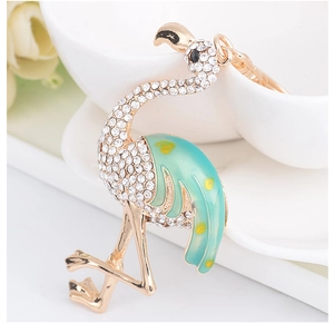 Détail du porte-clés flamant rose avec strass blancs et émail vert sur métal doré