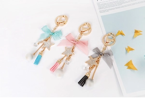 Detailed macro view of mint green, pink, and grey star tassel keychains with bows