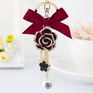 Elegant gold keychain with red bow, rhinestone rose, black clover and camellia pearl charm