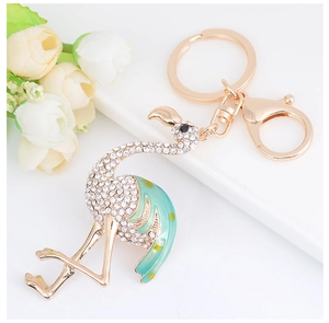 Détail du porte-clés flamant rose avec aile en émail vert et strass brillants sur métal doré