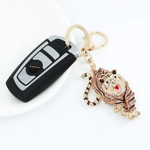 Golden tiger keychain with pink rhinestones and metal clasp on white background