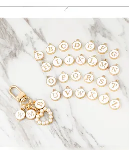 Golden alphabet letter charms set with pearl heart pendant on marble background