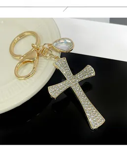 Close-up of golden cross keychain with crystal stones and teardrop pendant detail