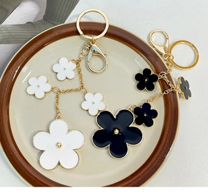Detail of floral enamel keychains with golden hardware in white and black flower designs