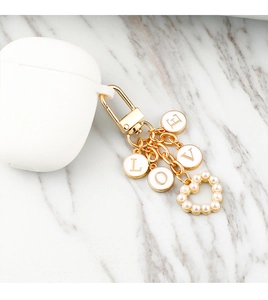 Detailed close-up of pearl heart and LOVE letter charms on a gold metal keychain