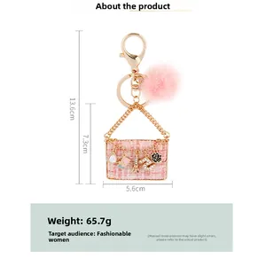 Pink tweed bag keychain detail with gold chain and size measurements in centimeters