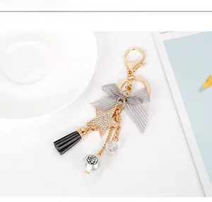 Close-up of star keychain with grey ribbon bow, black tassel and camellia bead