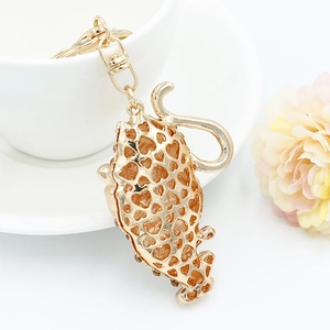 Golden zodiac tiger keychain with rhinestone heart cutouts hanging on a white coffee cup