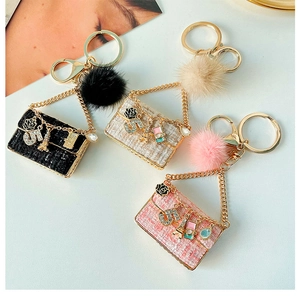 Macro view of tweed mini bag keychains with gold charms and fuzzy fur pom-poms