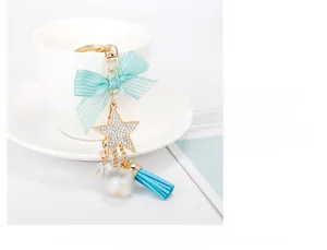 Detail of light blue bow keychain with sparkling star, pearl, and tassel on a white cup