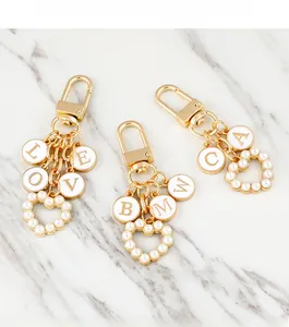 Detailed macro view of gold-plated keychains with pearl hearts and enamel alphabet charms