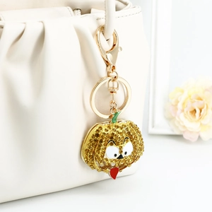 Sparkling Halloween pumpkin keychain with yellow rhinestones on a white handbag