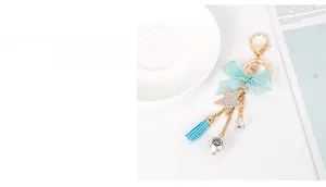 Detail of light blue bow keychain with rhinestone star and pearl charm on white surface